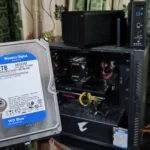 Người dùng cầm ổ cứng trước dàn PC và NAS TerraMaster, minh họa vấn đề thiếu khe cắm lưu trữ