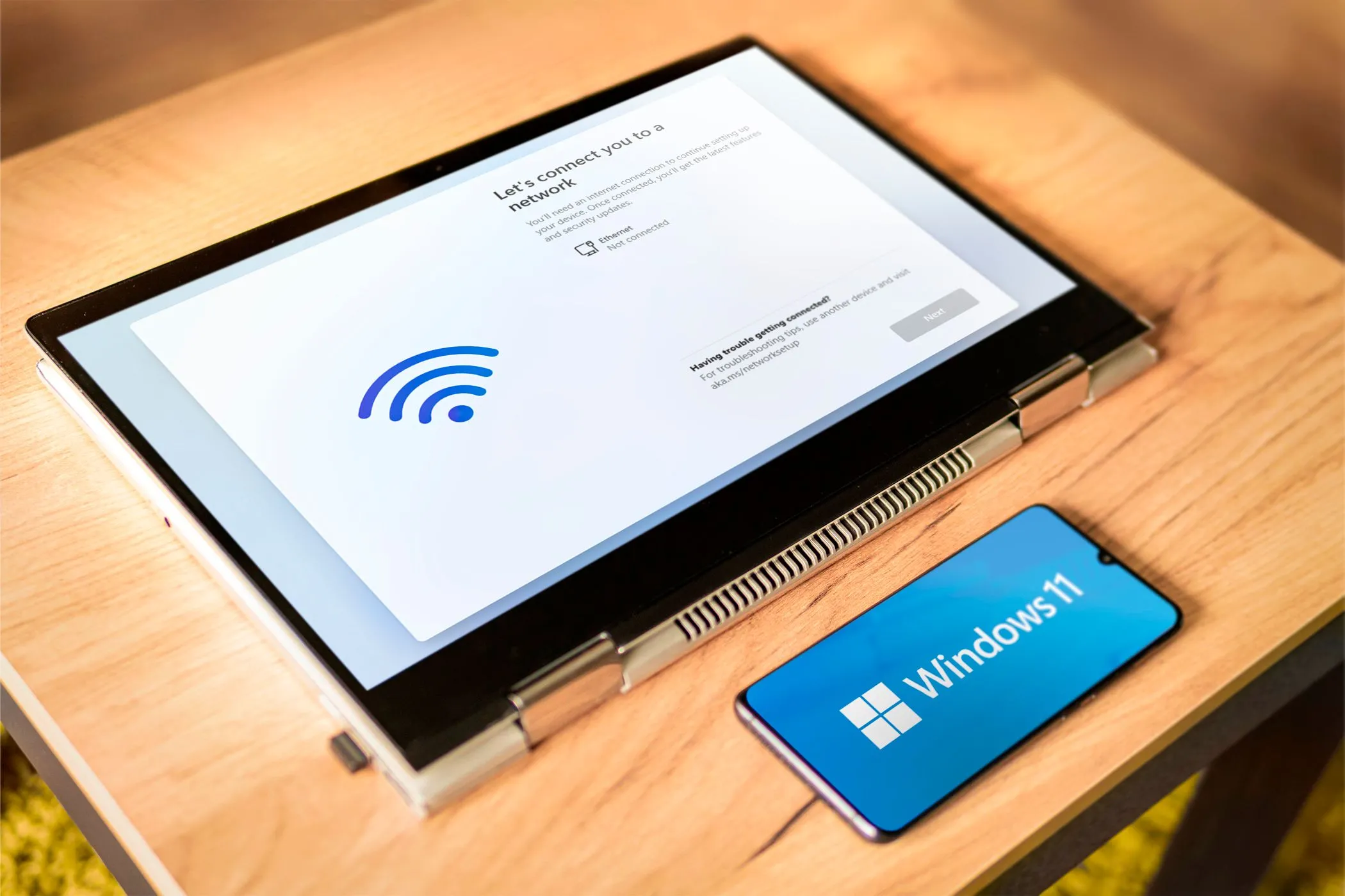 Điện thoại Android và máy tính xách tay hiển thị logo Windows 11, minh họa khả năng điều khiển máy tính từ xa