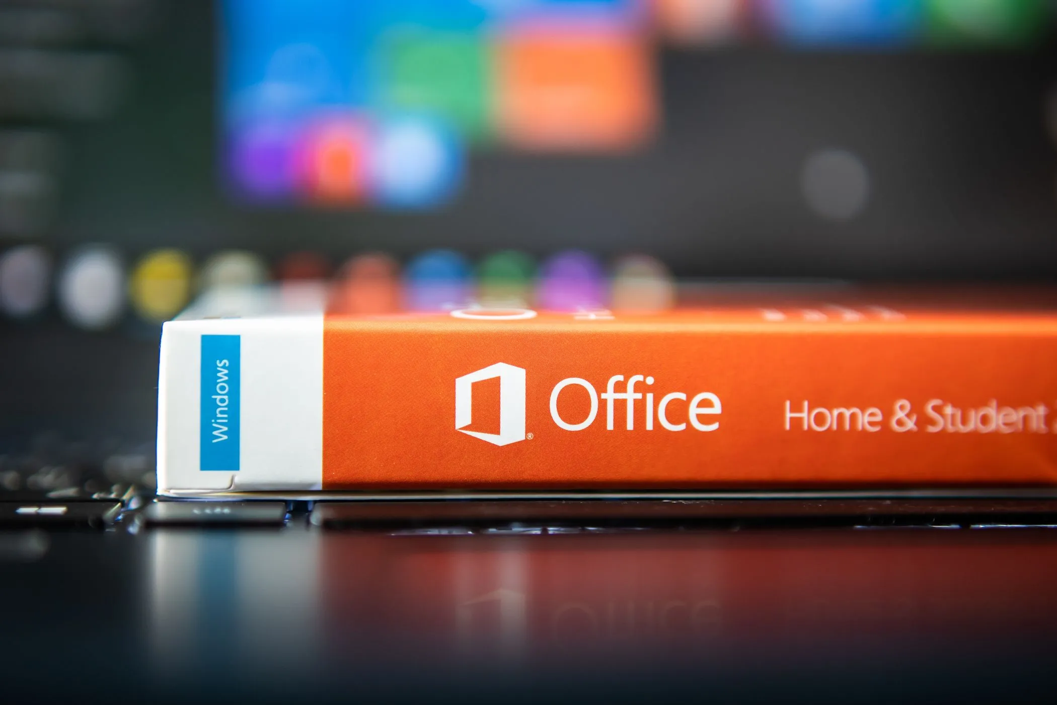 Người dùng đang xem xét hộp đựng phần mềm Microsoft Office Home and Student phiên bản vật lý trên bàn làm việc