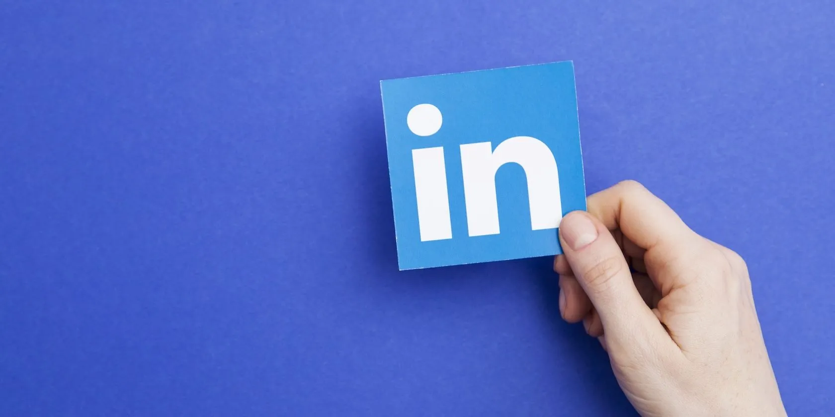 Biểu tượng LinkedIn được cầm trên tay, minh họa ứng dụng thu thập dữ liệu nghề nghiệp và thông tin hệ thống