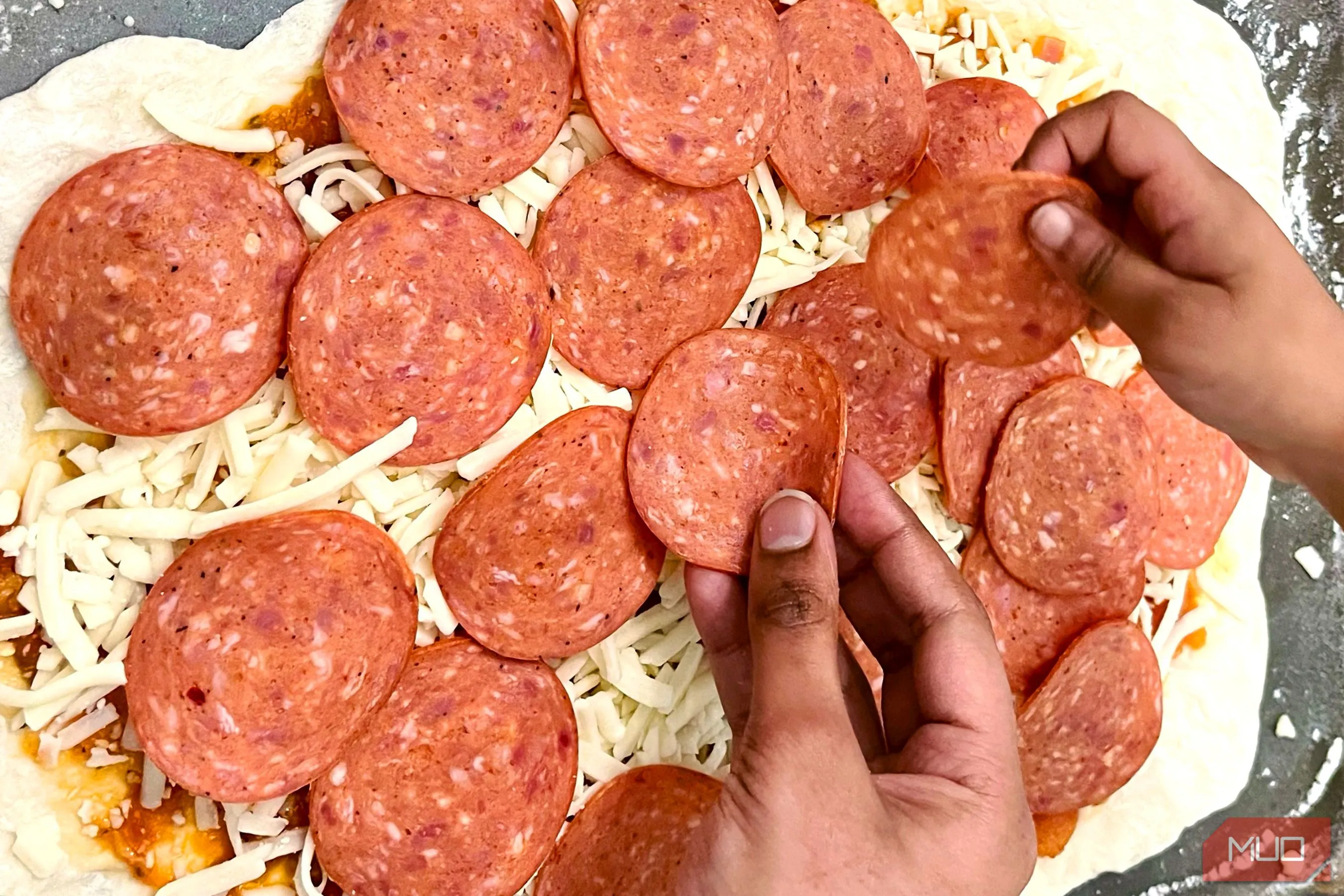 Đôi bàn tay đang chuẩn bị món pizza, tạo nên câu chuyện và cảm xúc cho bức ảnh ẩm thực