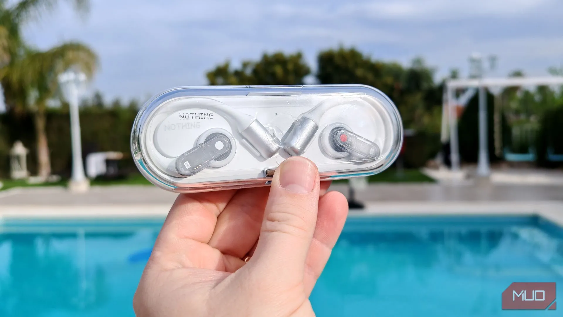 Hộp sạc trong suốt của Nothing Ear (open) được cầm trên tay ngoài trời