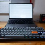 Keychron K8 Max đặt trên bàn làm việc cùng MacBook, thể hiện sự chắc chắn của khung nhôm.