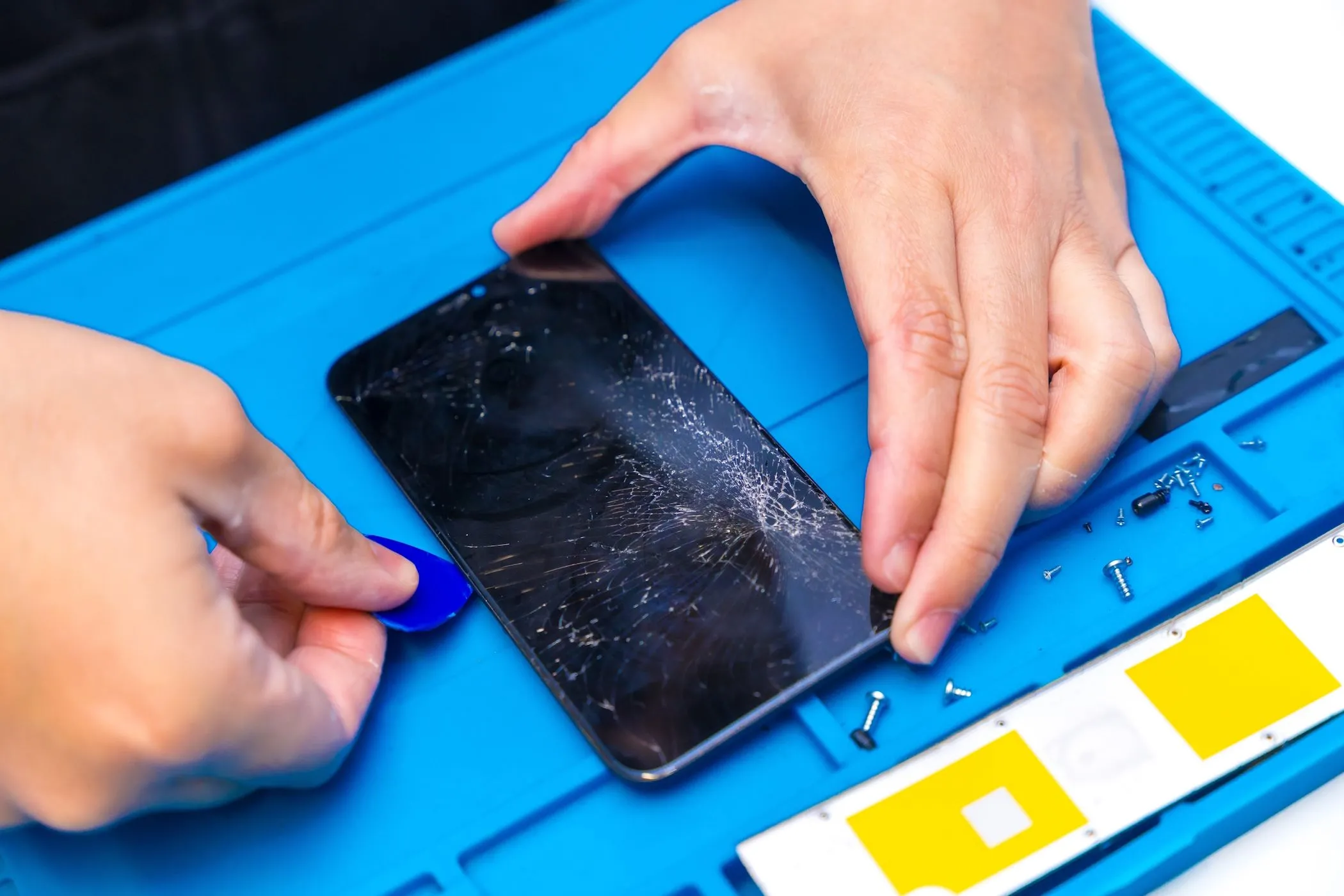 Kỹ thuật viên đang tháo dỡ một chiếc smartphone để sửa chữa tại trung tâm bảo hành.