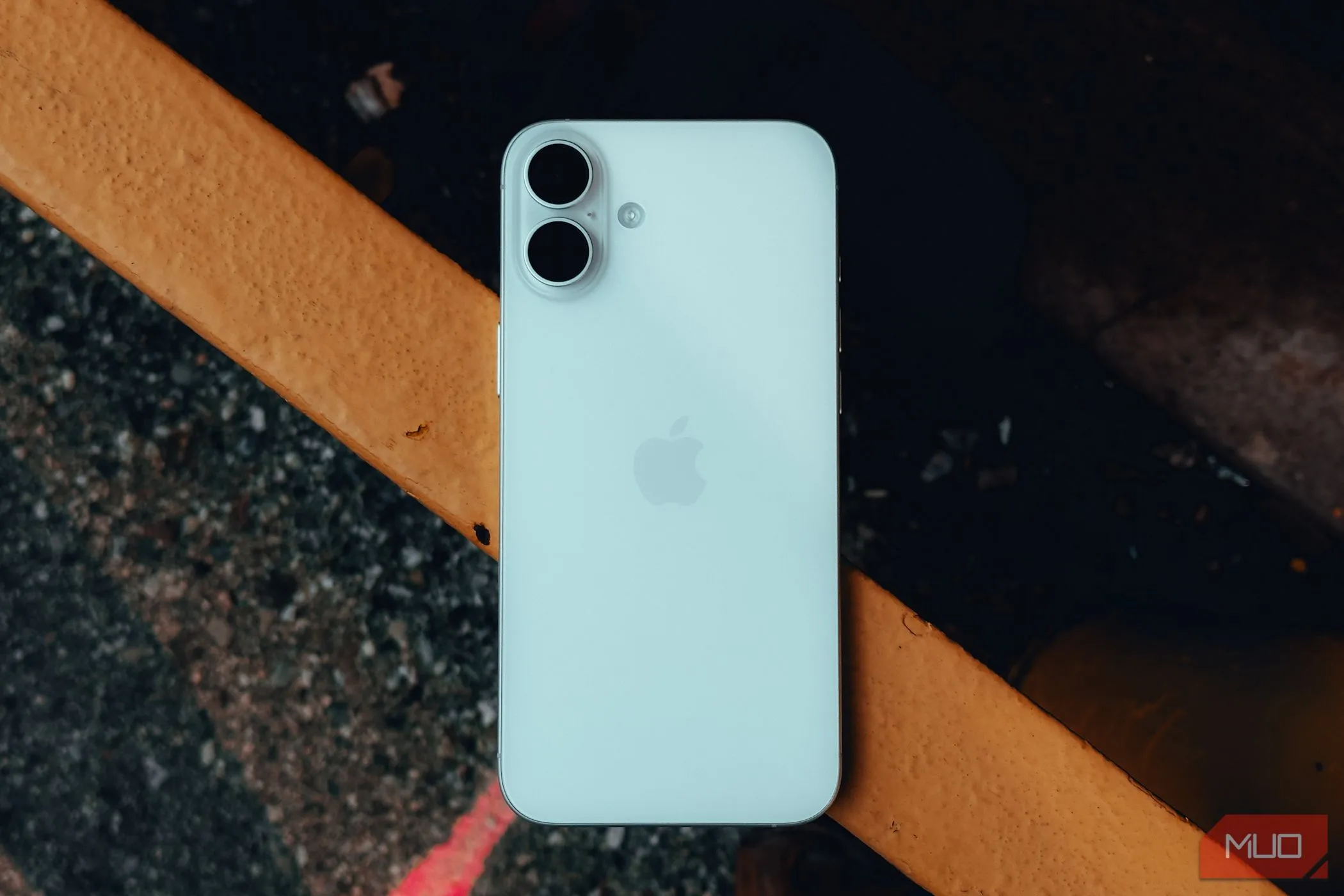 Mặt lưng của iPhone 16 Plus đặt trên lan can, minh họa vị trí chạm cho tính năng Back Tap