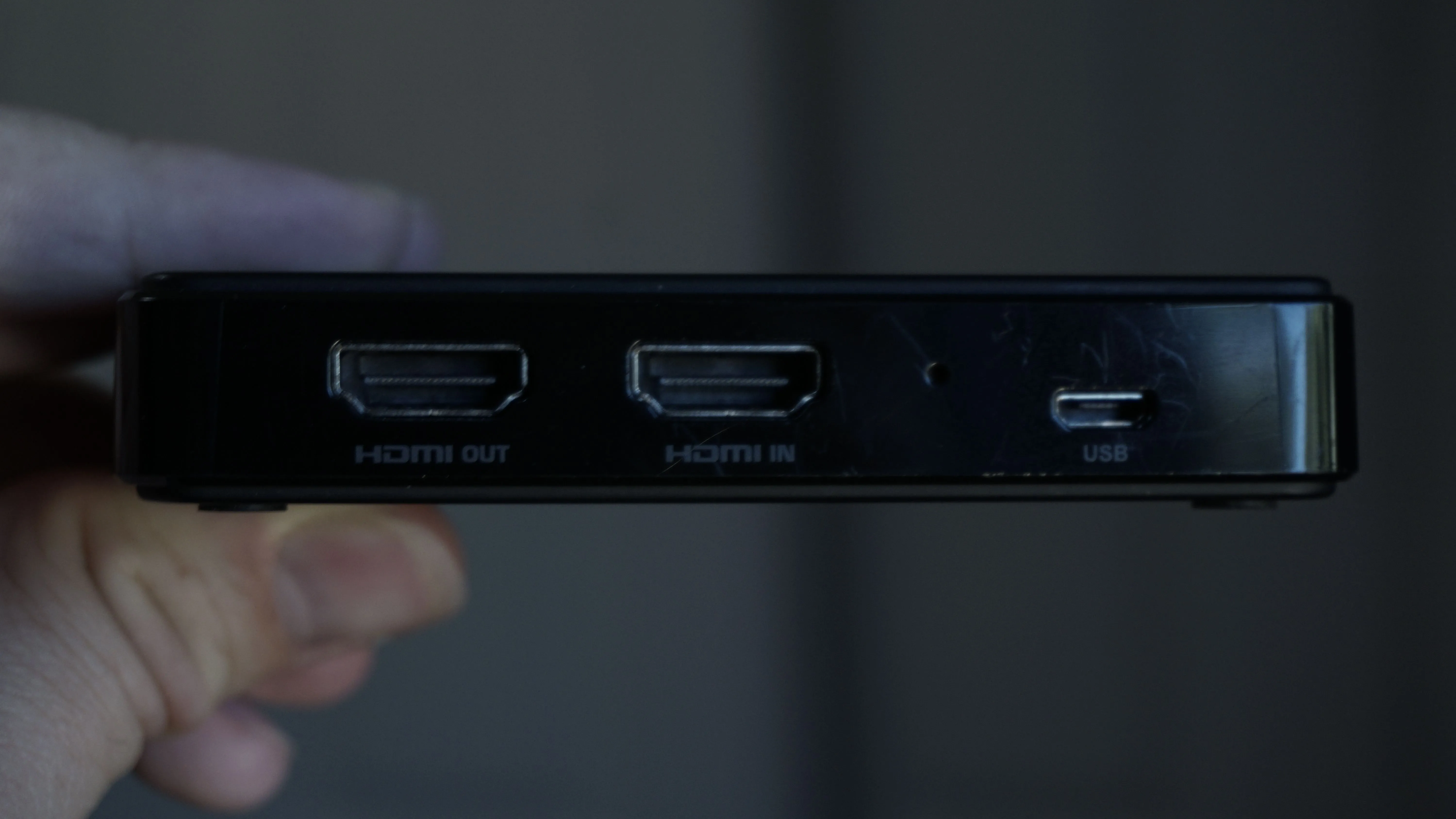 Một người đang cầm thẻ thu hình, cho thấy các cổng HDMI in/out và USB của nó.