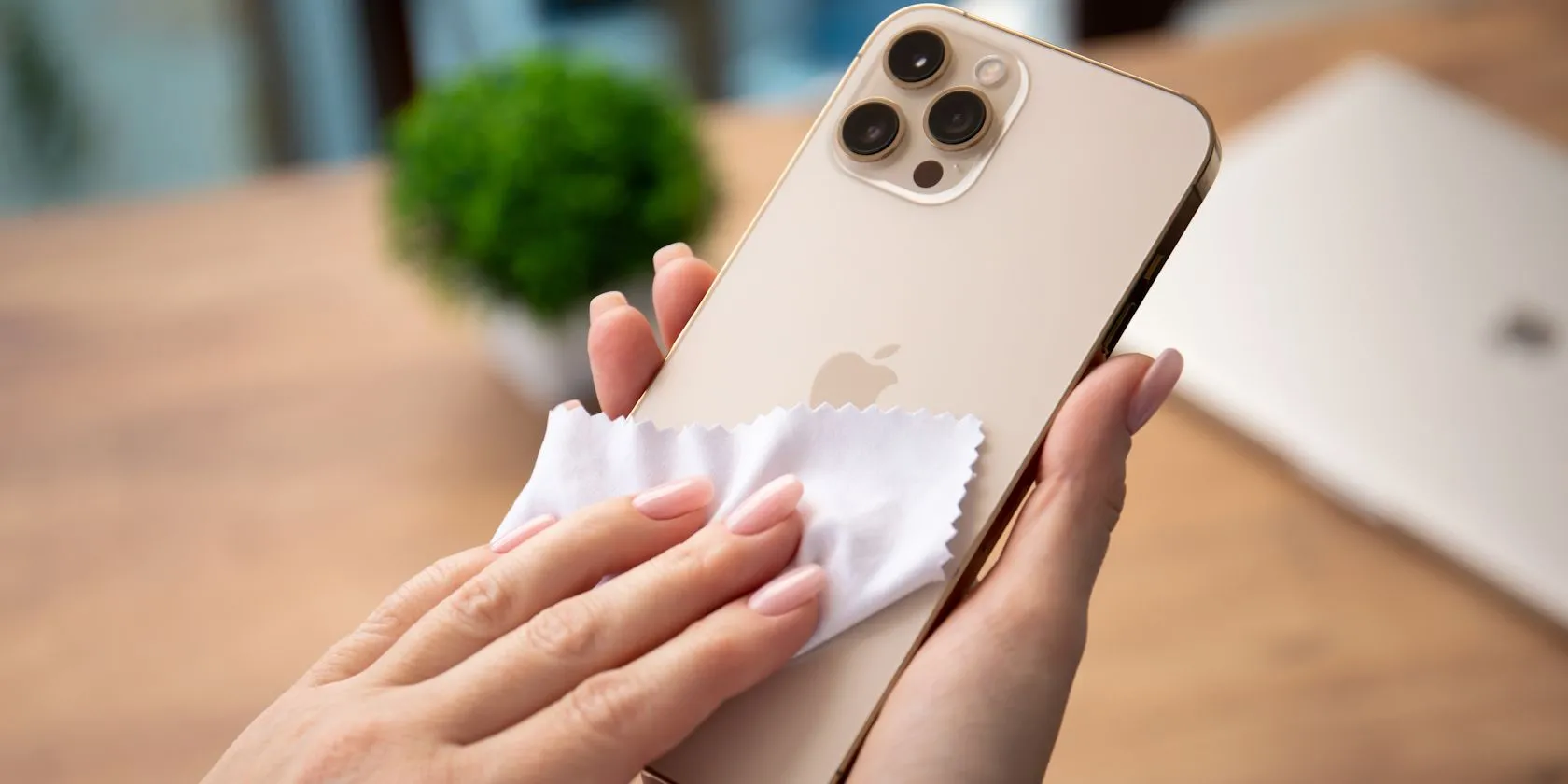 Người phụ nữ đang vệ sinh màn hình iPhone bằng khăn microfiber, cách làm đơn giản và hiệu quả hơn các bộ vệ sinh cao cấp.