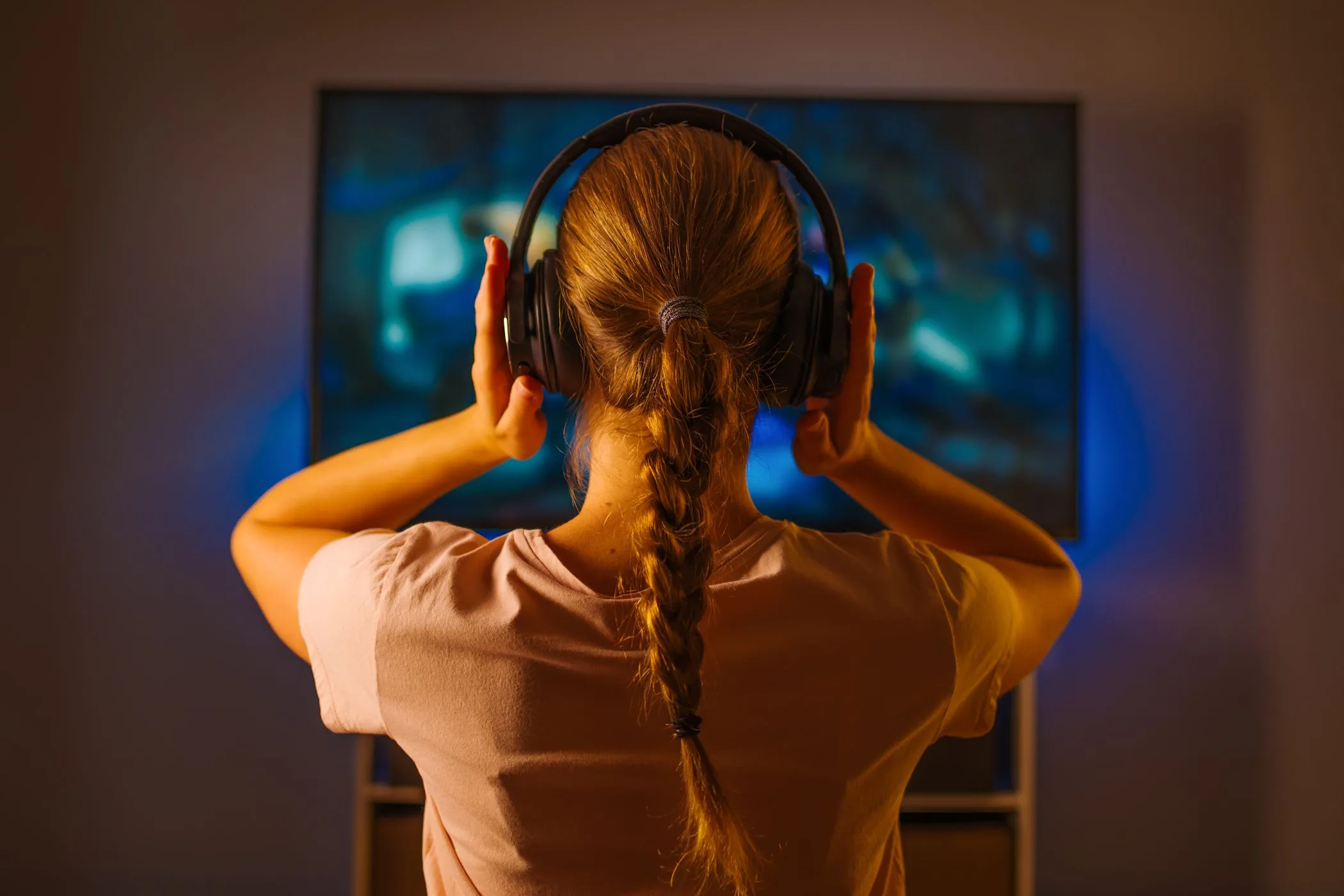 Người phụ nữ trẻ đeo tai nghe đang tập trung xem TV, nâng cao kỹ năng nghe và trải nghiệm âm thanh sống động.