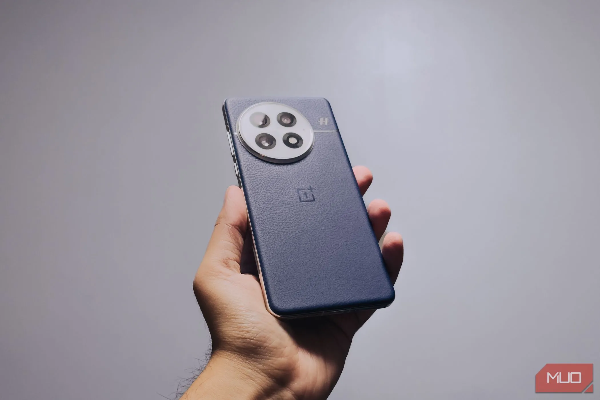 OnePlus 13 trong tay người dùng, góc nghiêng trên nền trắng, nổi bật cảm giác cầm nắm.