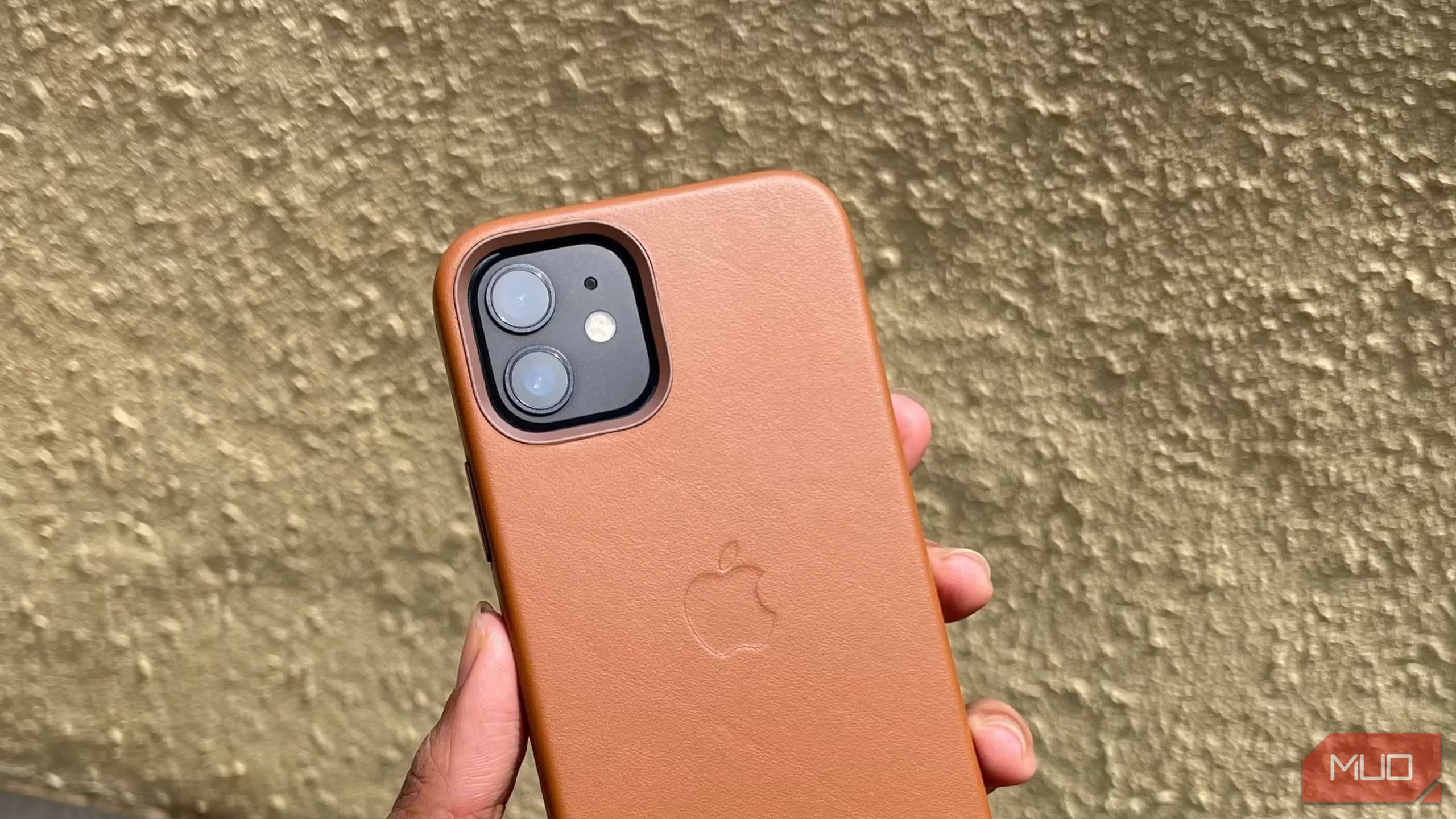Ốp lưng iPhone 12 bằng da màu nâu vàng trên tay người dùng