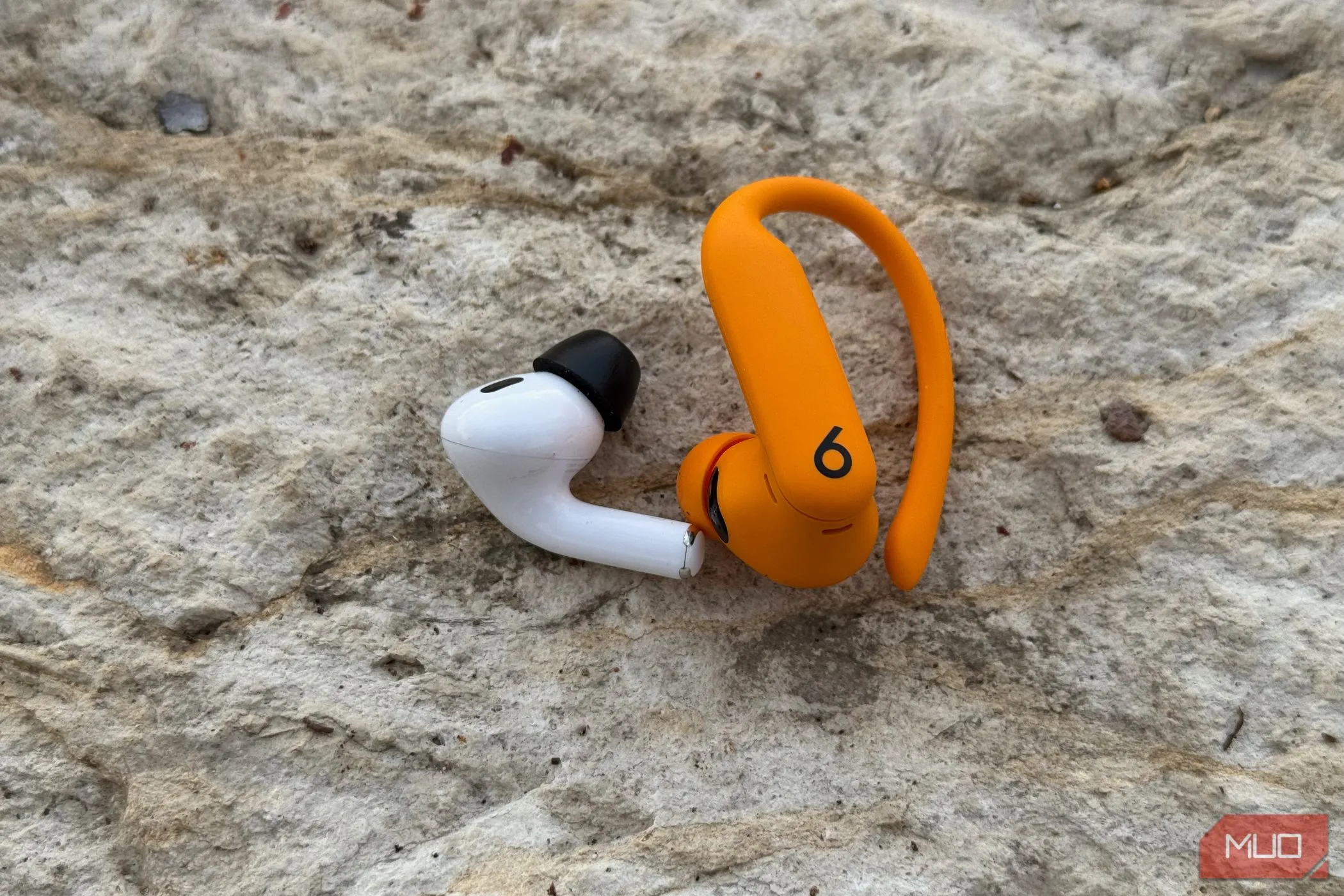 So sánh kích thước và thiết kế giữa tai nghe AirPods Pro 2 và Powerbeats Pro 2, thể hiện sự khác biệt về trọng lượng và cảm giác đeo.