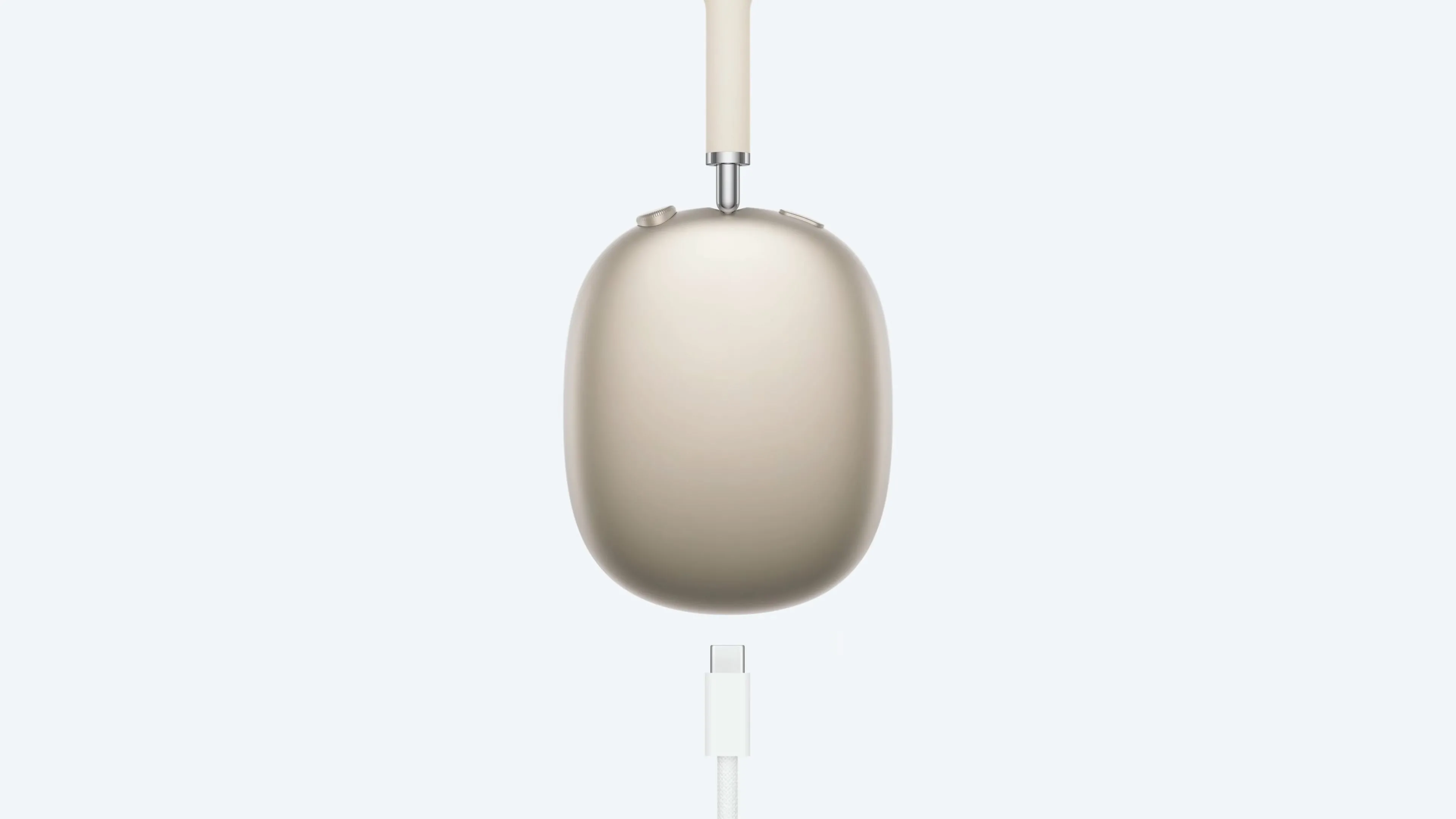 Tai nghe AirPods Max màu Starlight với cáp USB-C, minh họa việc cắm sạc nhưng không thể sử dụng đồng thời